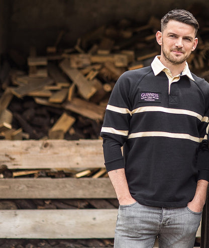 A man and a woman standing next to a pile of wood wearing authentic rugby jerseys in Guinness Traditional Rugby Jersey style.