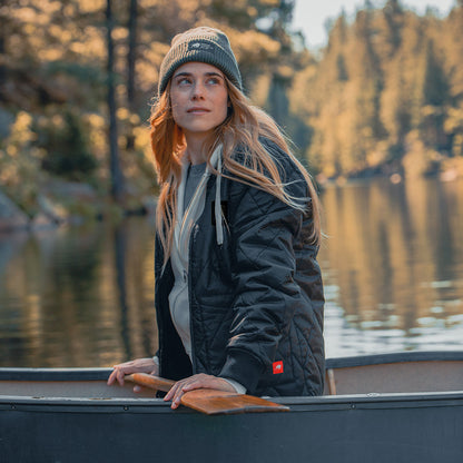 A woman sitting in a Guinness Quilted Utility Zip Up canoe on a lake.