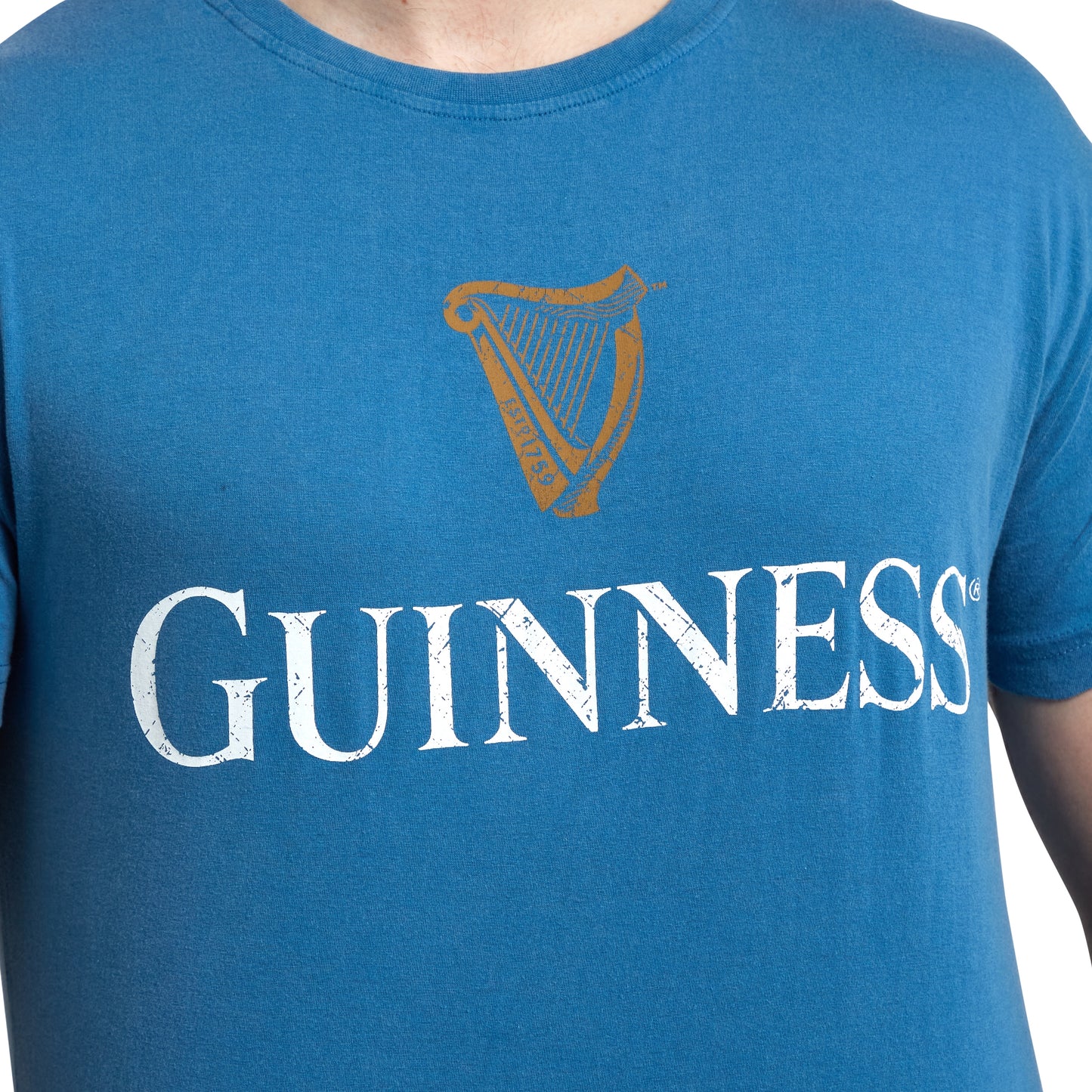 Person wearing a Blue Guinness Harp Premium Tee with a gold harp and the word "Guinness" printed in white text.