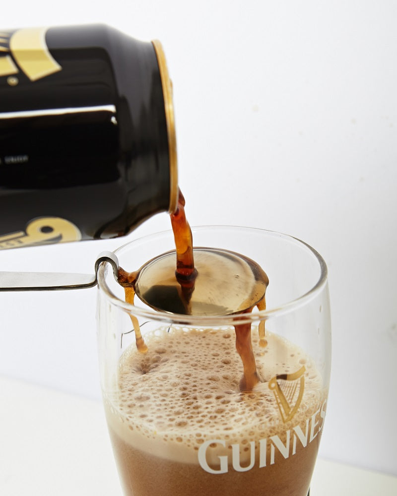 A can of Guinness being poured into a glass, using an Engraved Pouring Spoon.