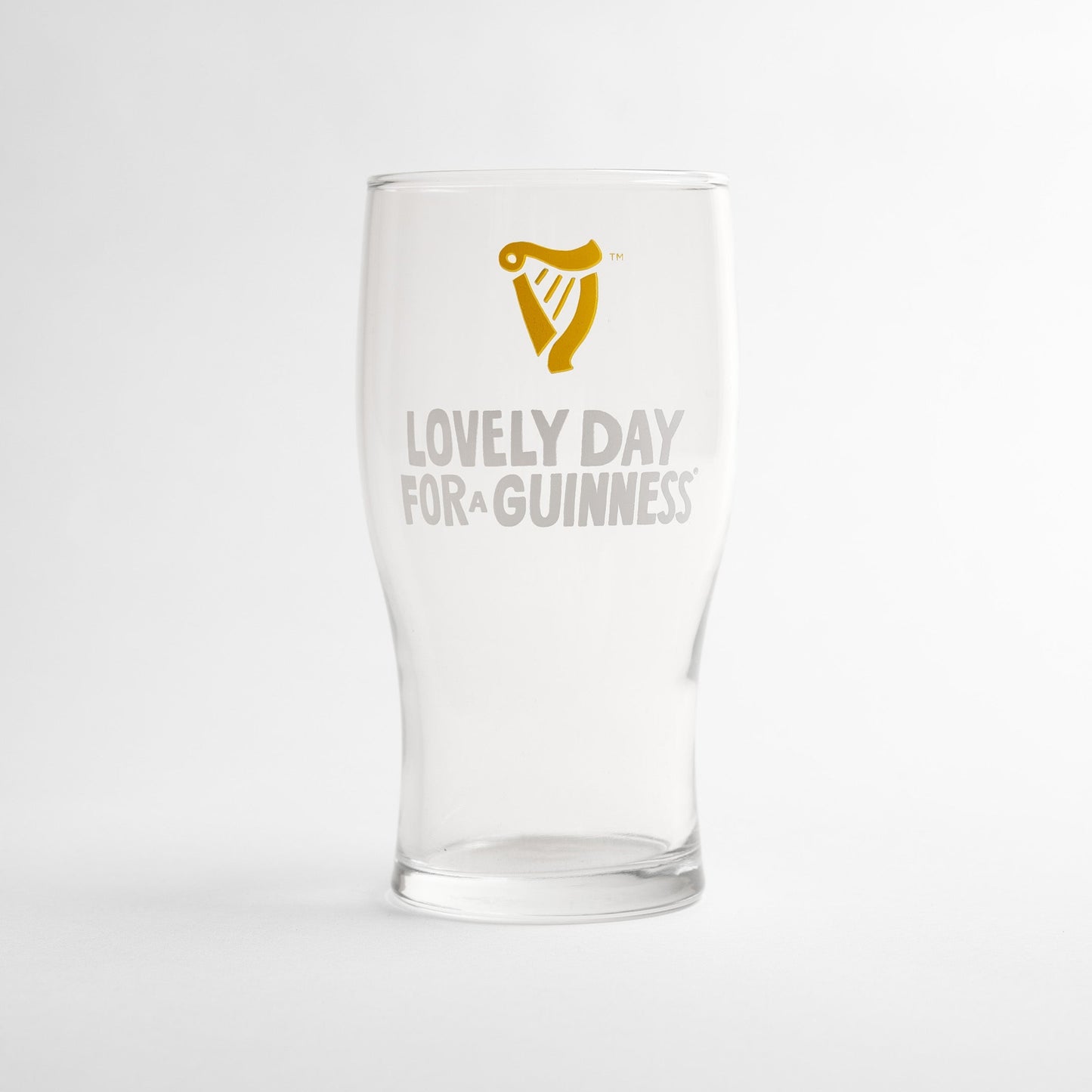 The Guinness Seb Curi Lovely Day Pint Glass from Guinness Webstore US is a collector’s edition pint glass featuring the iconic harp logo and "Lovely Day for a Guinness" on the front.
