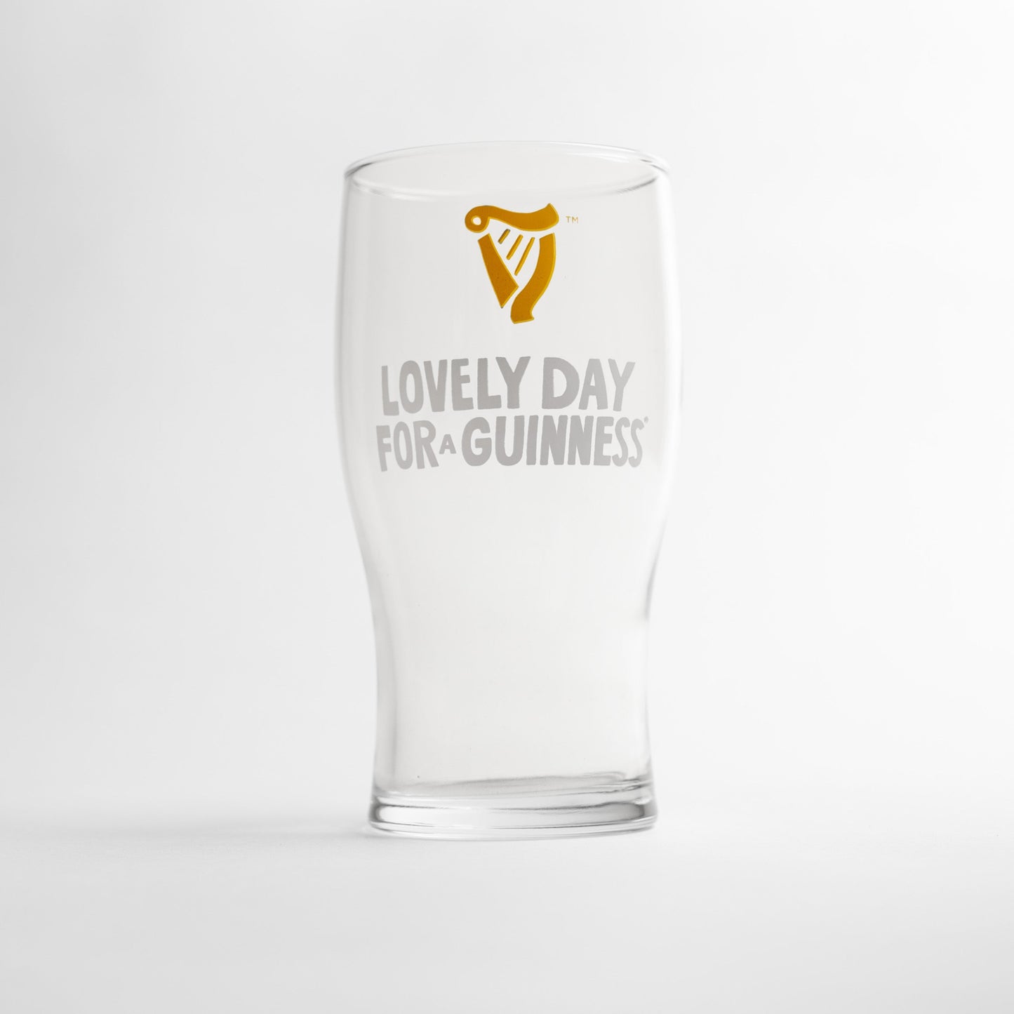 The Guinness Seb Curi Lovely Day Pint Glass from Guinness Webstore US is a clear collector’s edition featuring the harp logo and "Lovely Day for a Guinness" in white and gold.