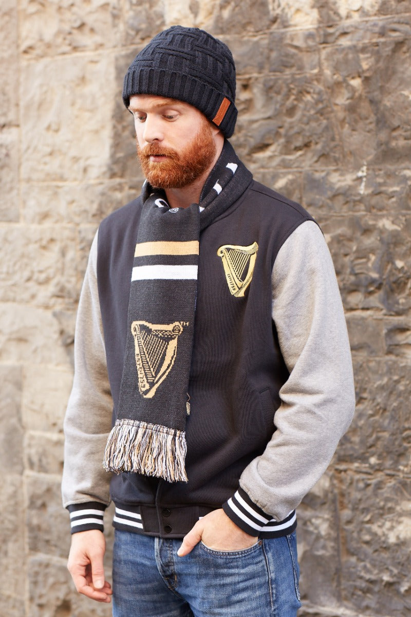 A man with a beard wearing a Guinness Black Leather Patch Beanie made of soft yarn.