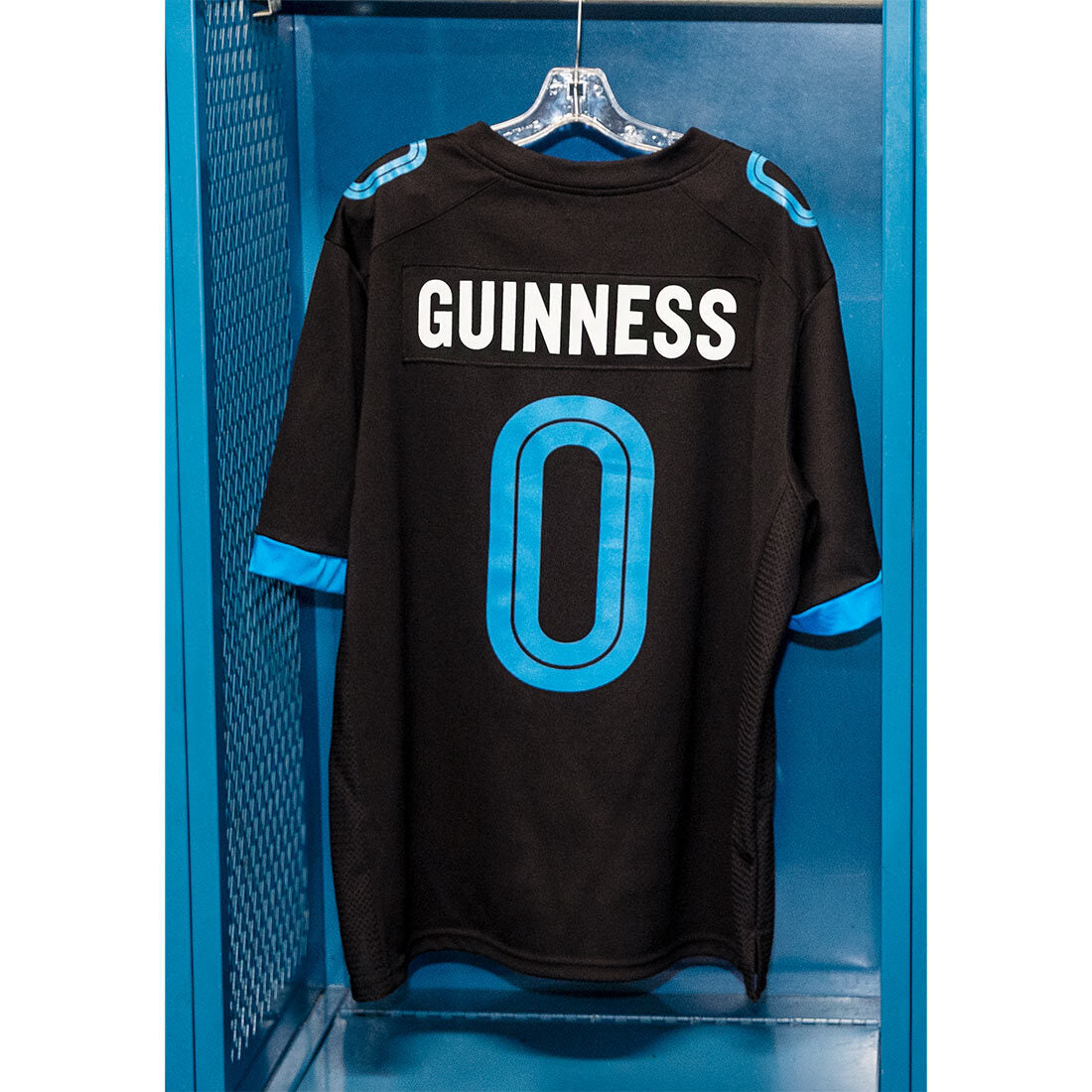 A Guinness 0 Football Jersey - Black with the number 0 hanging in a locker. (By Guinness Webstore US)