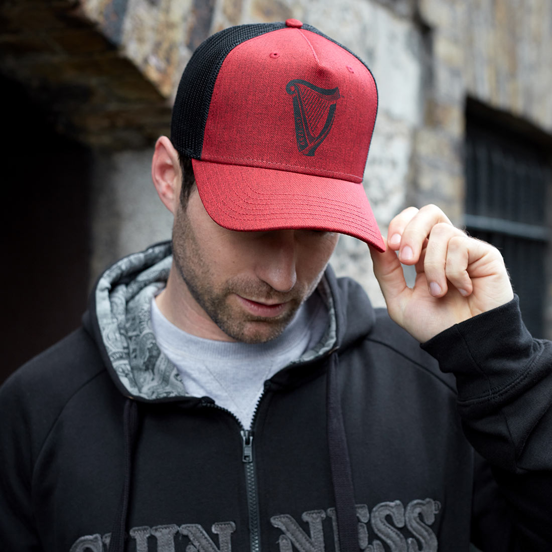 A man wearing a Guinness Trucker Premium Black & Red Harp Cap.