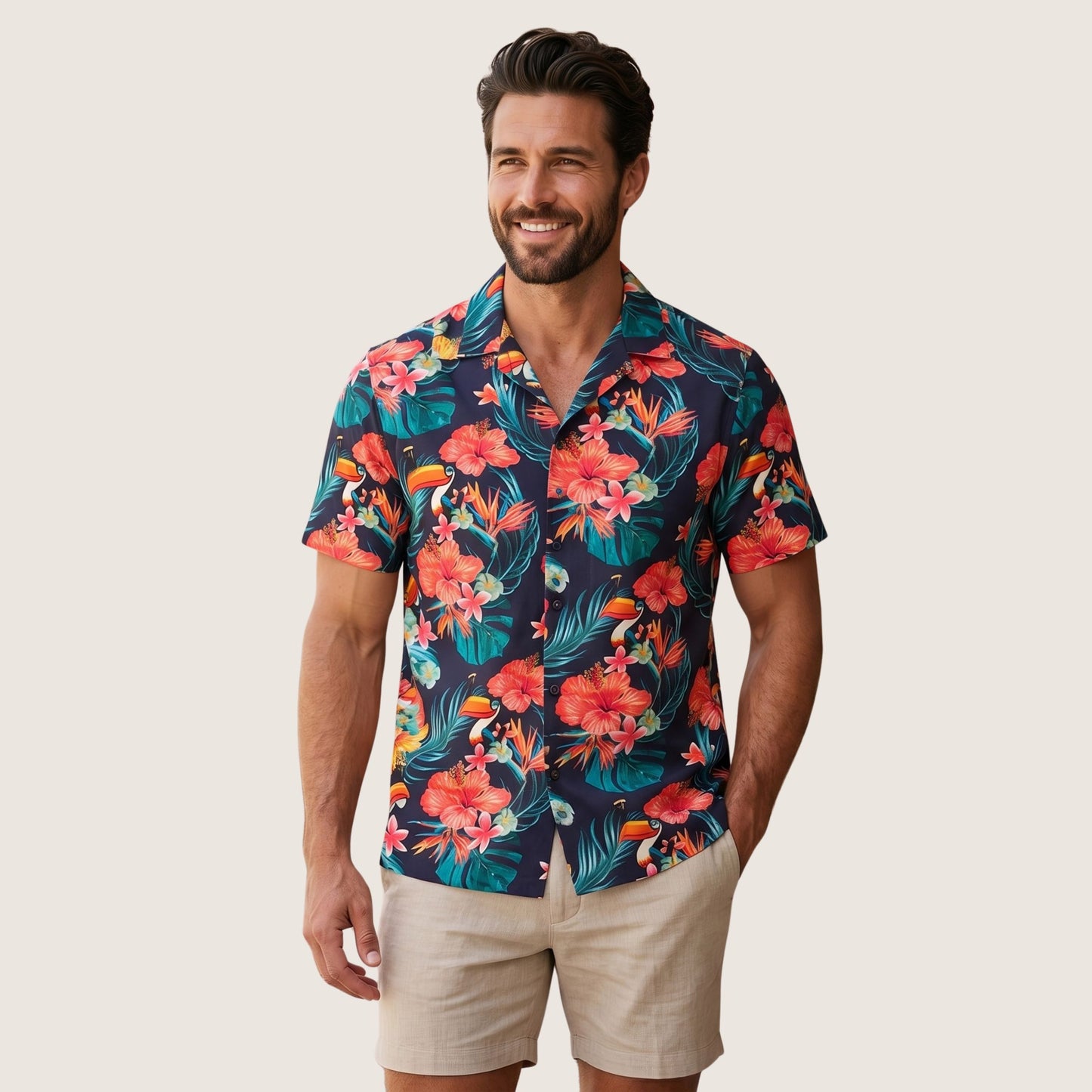 A man wears a Guinness Toucan Hawaiian Shirt—navy with red and orange floral print from Guinness—and beige shorts, standing against a plain light background.