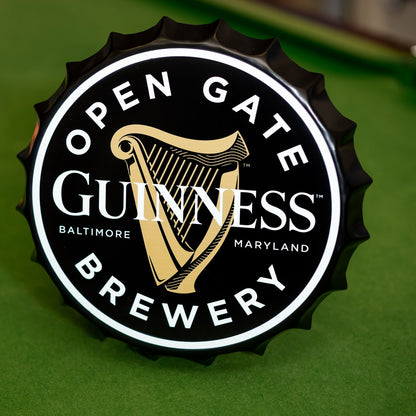 Open the Guinness Open Gate Brewery Bottle Top Metal Sign merchandise and find a bottle cap.