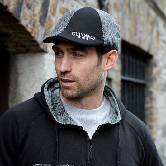 A man wearing a Guinness hoodie and a Guinness paneled Ivy cap.