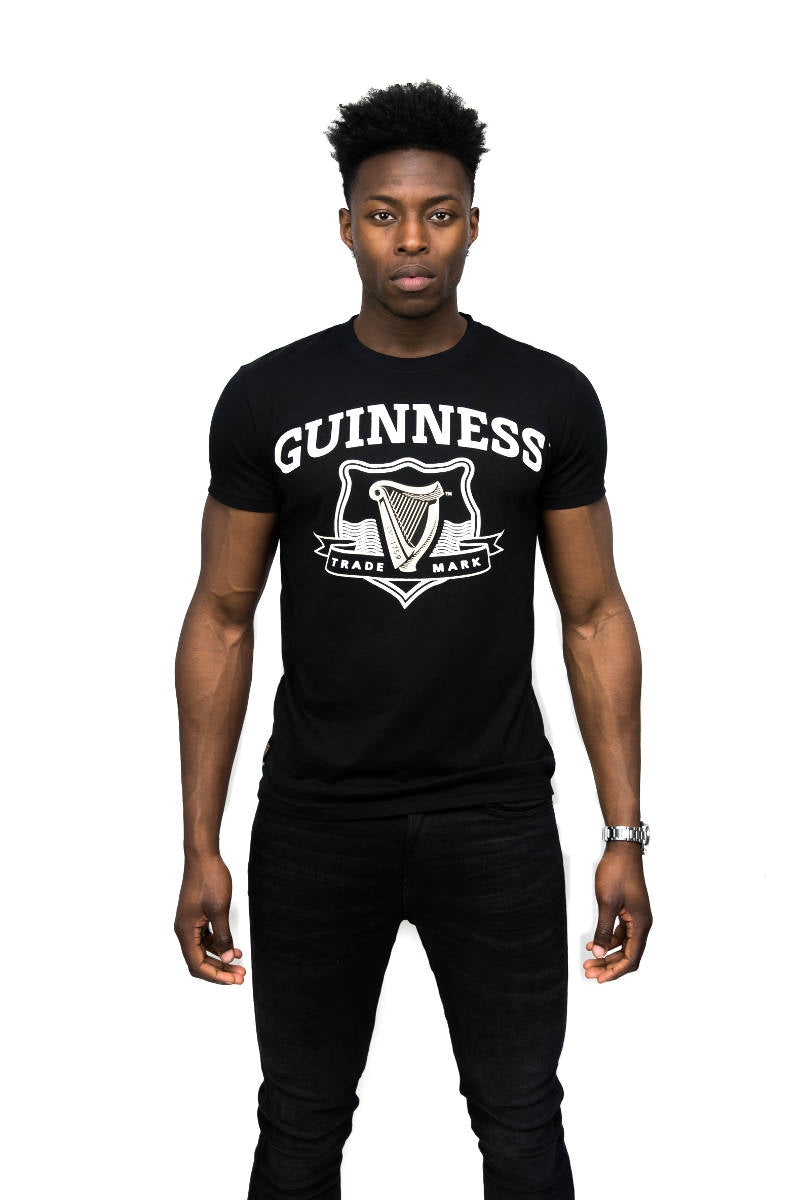 A man wearing a 100% cotton black Guinness Signature Black Trademark Label Tee.
