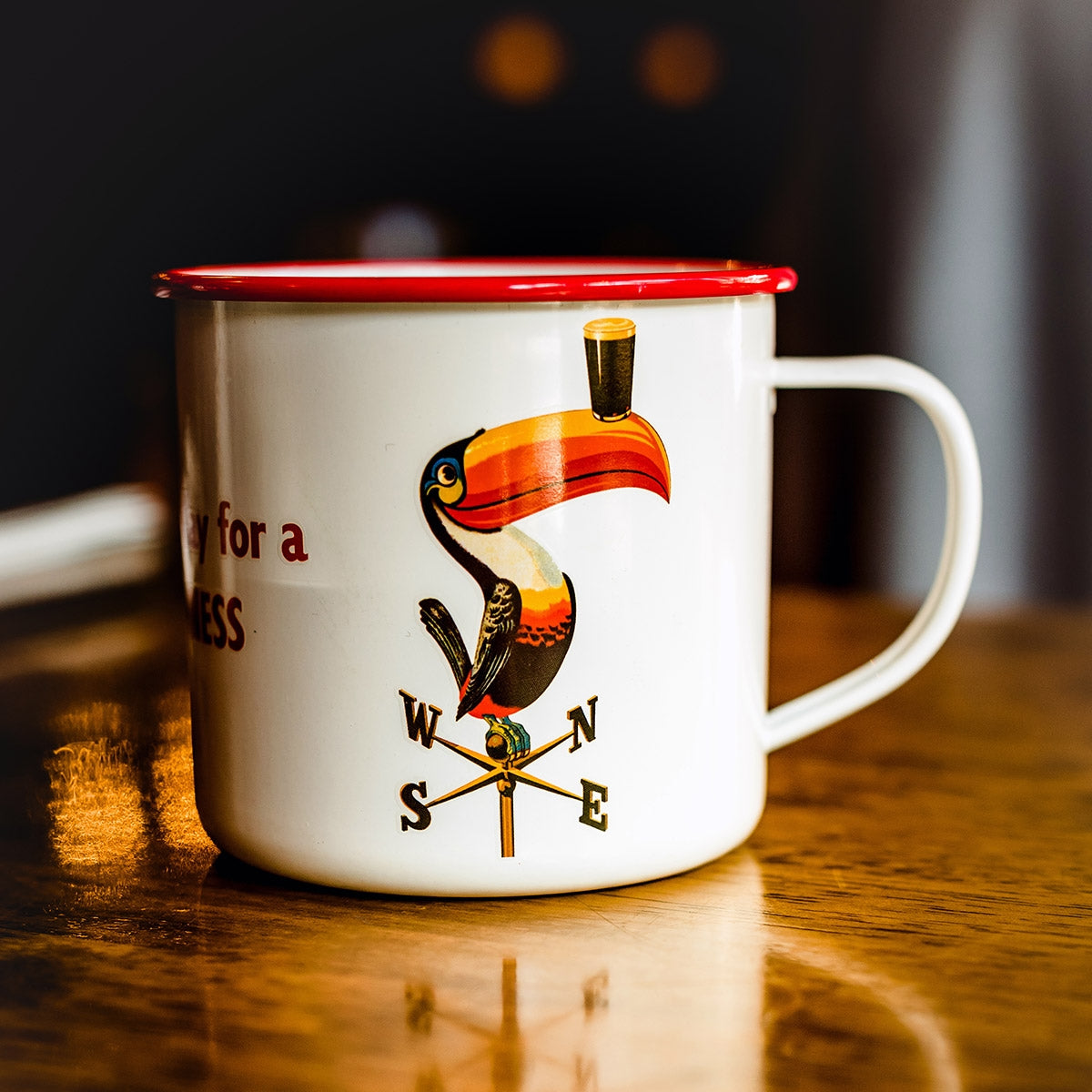 A Guinness Enamel Toucan Mug sits on a table.