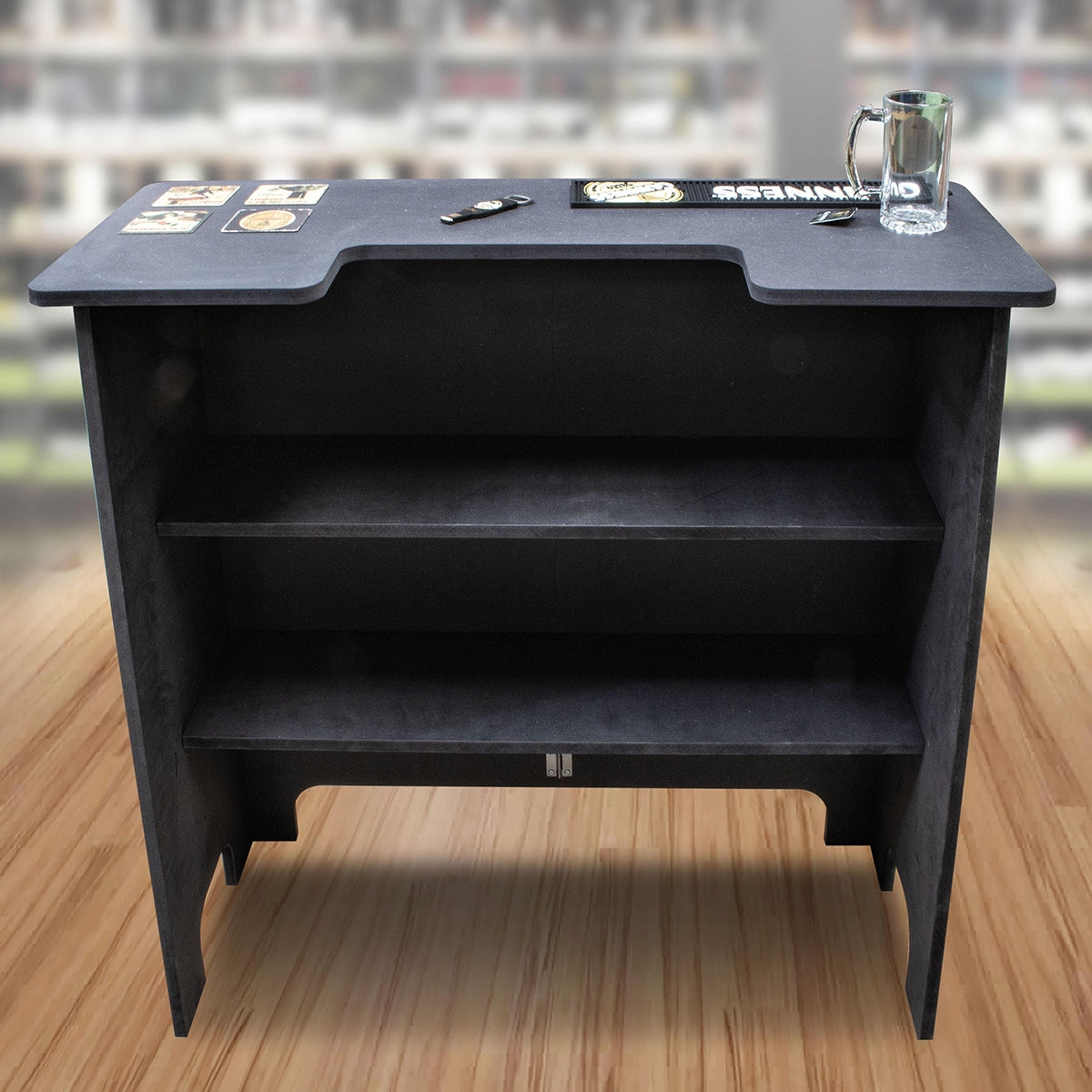 A Guinness Home Bar featuring a black bar with shelves and a glass on top.