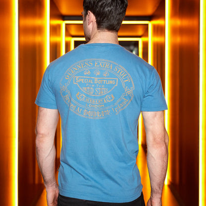 A man wearing a Guinness Trademark Label T-Shirt Blue standing in a hallway.