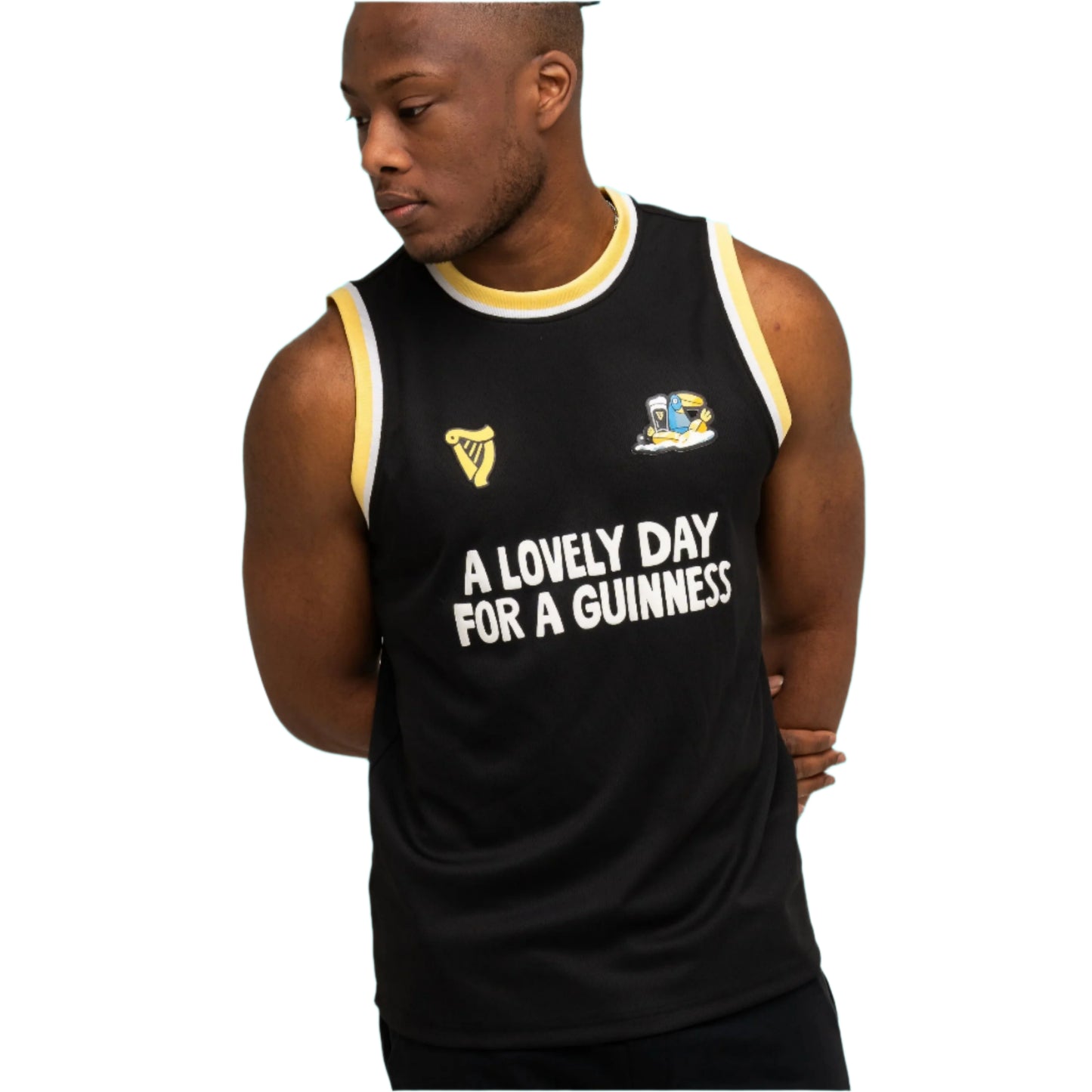 A man wears the Guinness Seb Curi Basketball Jersey from Guinness Webstore US—a black limited-edition jersey with yellow and white trim reading "A LOVELY DAY FOR A GUINNESS"—while standing against a plain background.