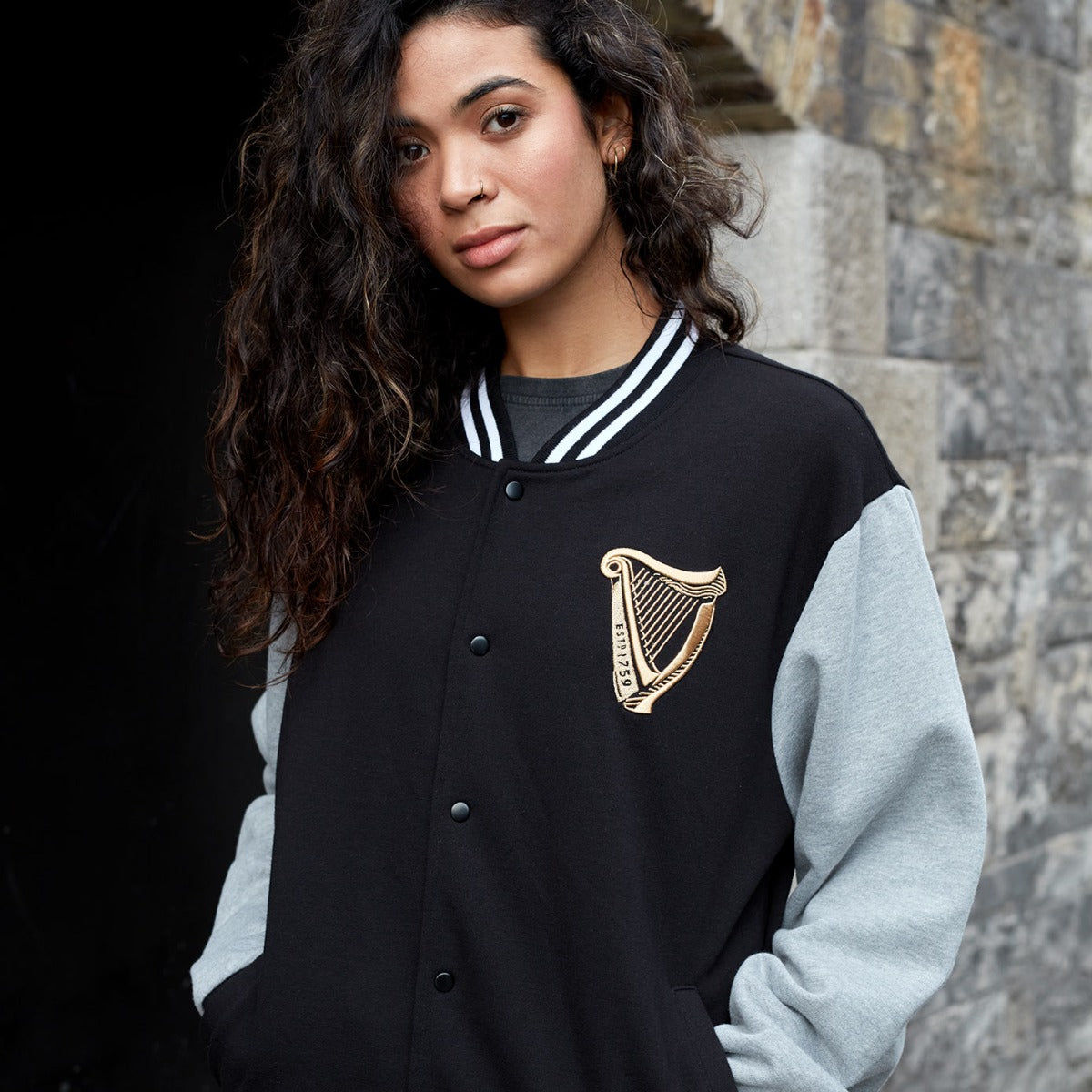 A woman wearing a Guinness black and gold varsity jacket.