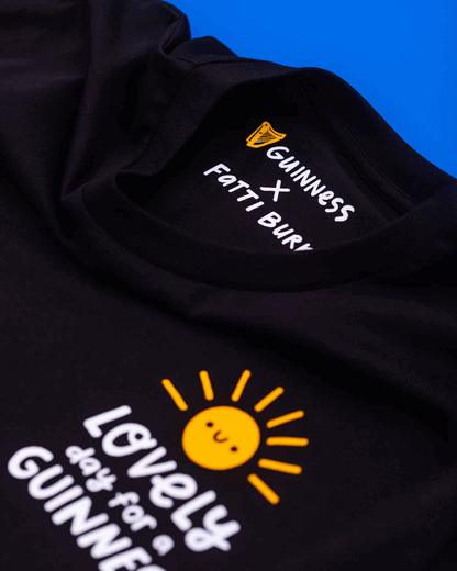 A FATTI BURKE "LOVELY DAY FOR A GUINNESS" black tee featuring a vibrant sun and the iconic Guinness logo, perfect for summer vibes.