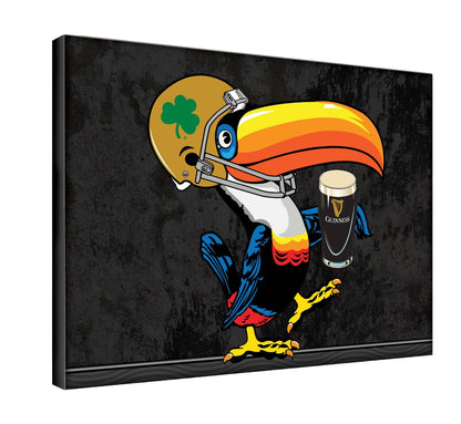 A toucan holding a Guinness beer surrounded by a Notre Dame backdrop on a Guinness Notre Dame Toucan Landscape Canvas Wall Art.