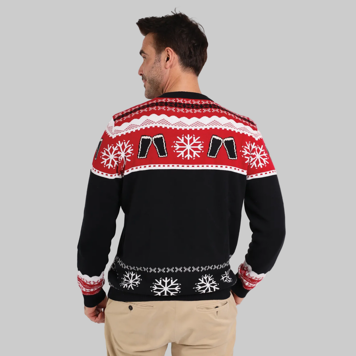 A man faces away, wearing the Official Guinness Holiday Sweater by Guinness featuring red, white, and black patterns with snowflakes and festive shapes—an ideal addition to your holiday wardrobe.