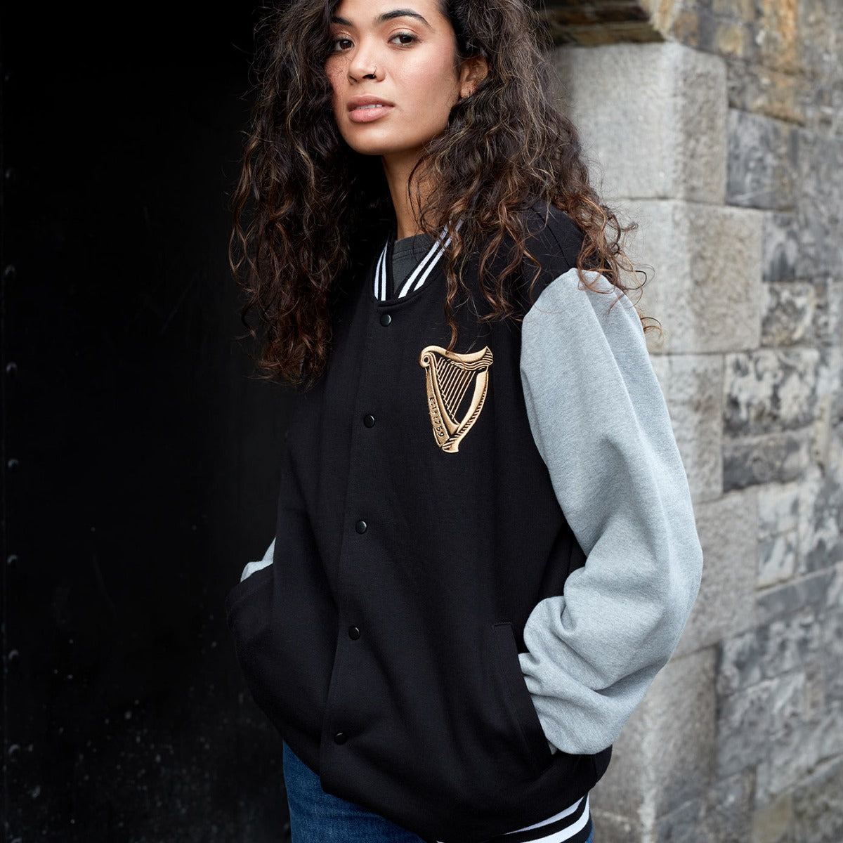 A woman wearing a Guinness Letterman Jacket.