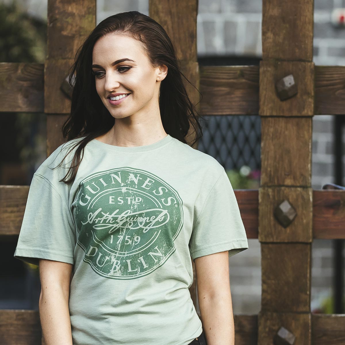 A young woman wearing a cotton blend Guinness Green Bottle Cap Tee by Guinness.