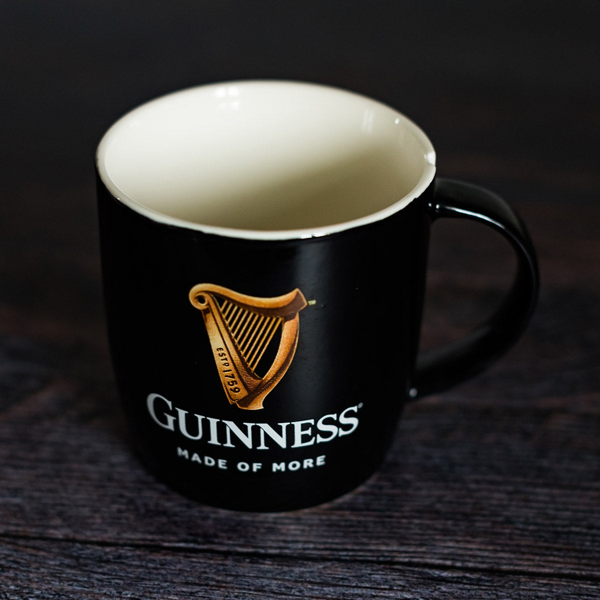 Guinness Black Mug with Official Harp Logo by Guinness on a wooden table.