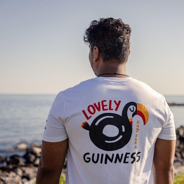 A man wearing a summer t-shirt with the word FATTI BURKE "LOVELY DAY FOR A GUINNESS" TOUCAN WHITE TEE.