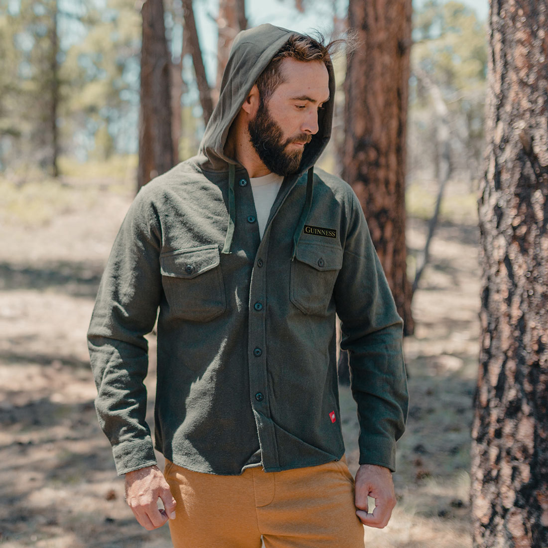 A man wearing a Guinness Deep Green Shirt Jacket in the woods.