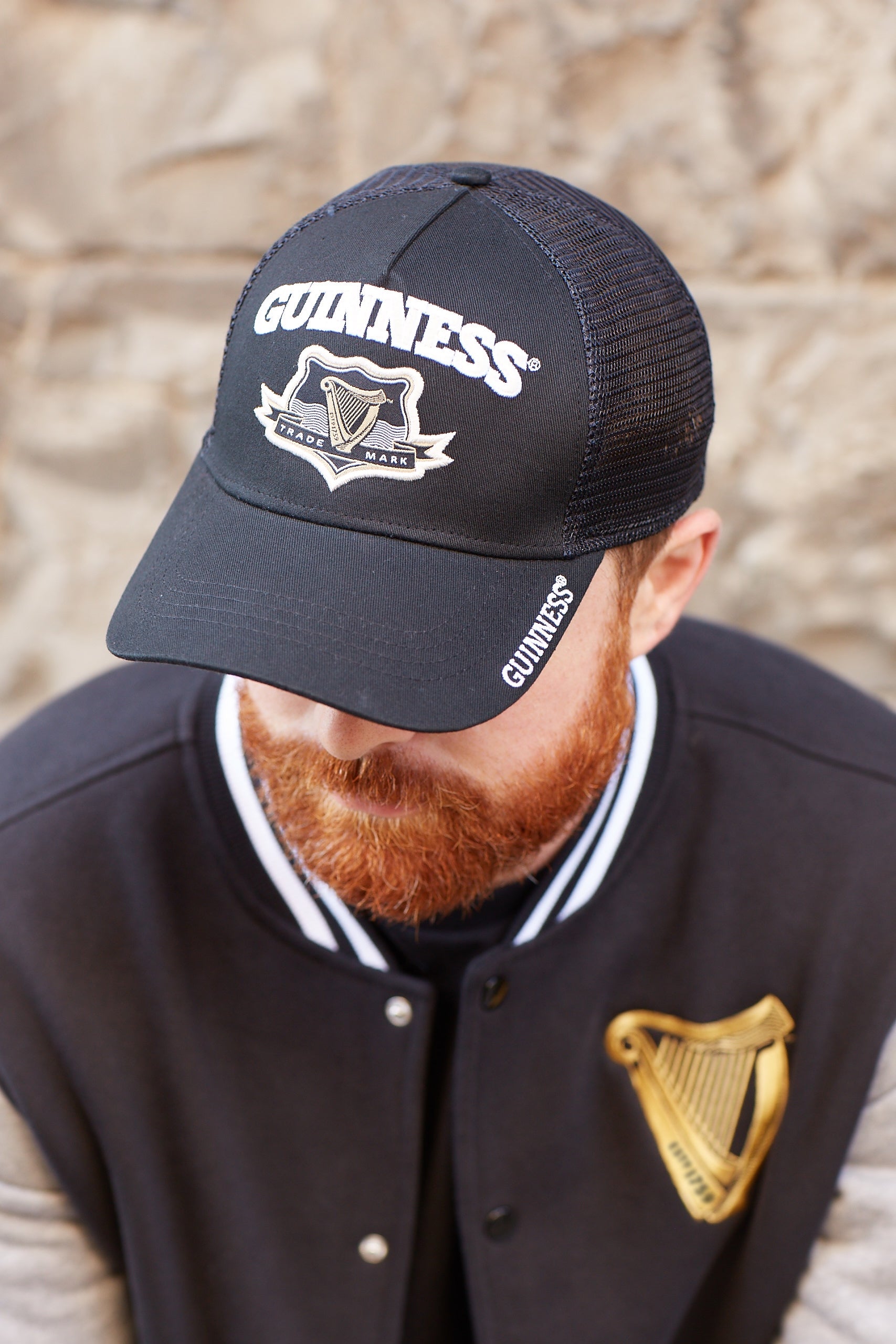 A bearded man wearing a Guinness Signature Black Trucker Mesh Baseball Cap Adjustable baseball cap.