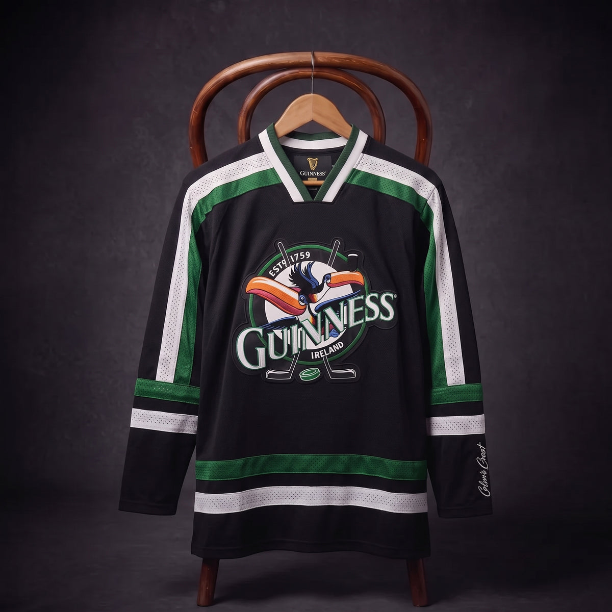 Displayed on a hanger over a wooden chair, the Guinness Toucan Hockey Jersey Black and Green features bold black and green colors with white stripes and the iconic Guinness logo showcasing the toucan. This stylish jersey from Guinness blends classic hockey design with legendary branding, perfect for fans of both the game and the brand.