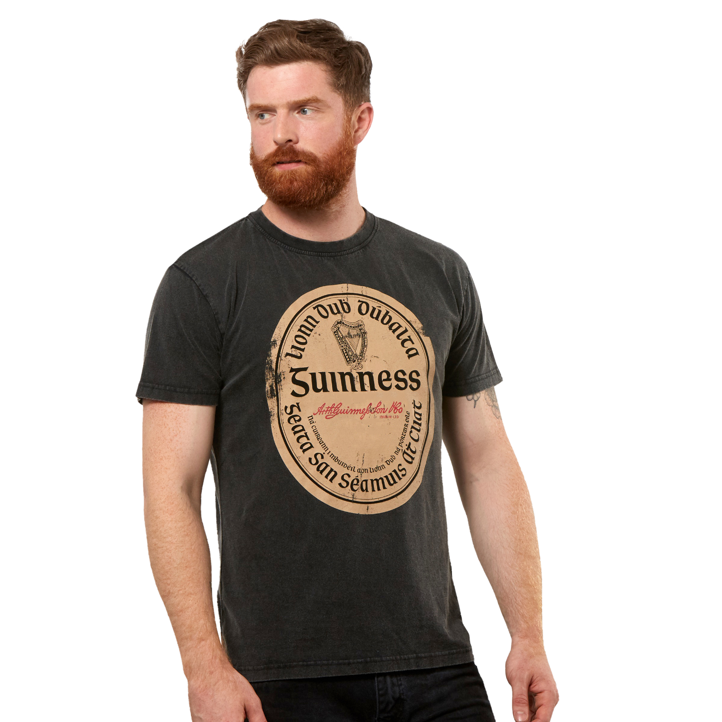 A man with a red beard wears the Guinness Black Distressed Label Tee, a unisex shirt featuring a large vintage-style graphic on the front.