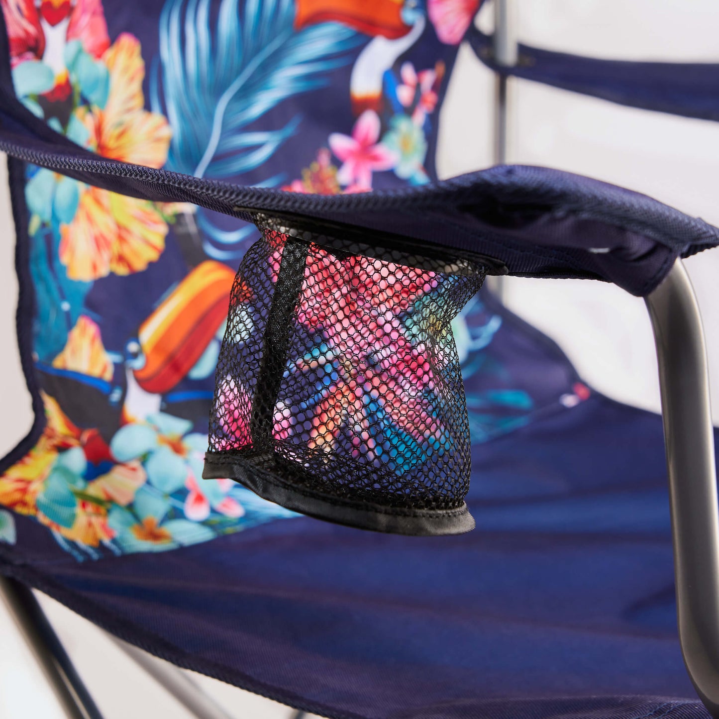 The Guinness Toucan Hawaiian Beach Chair by Guinness Webstore US features a blue foldable design with a vibrant floral pattern, mesh cup holder, and matching fabric accessory—ideal for your next beach outing.