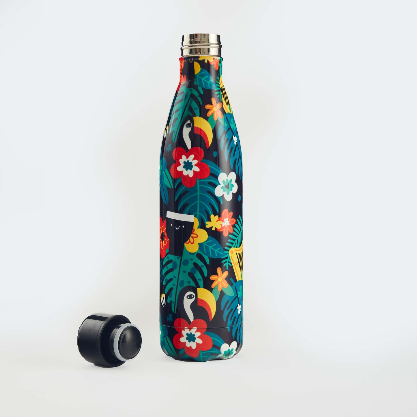 The Guinness x Fatti Burke Hawaiian Water Bottle, a BPA-free reusable flask with a vibrant tropical design, stands upright on a white background with its black cap placed beside it.