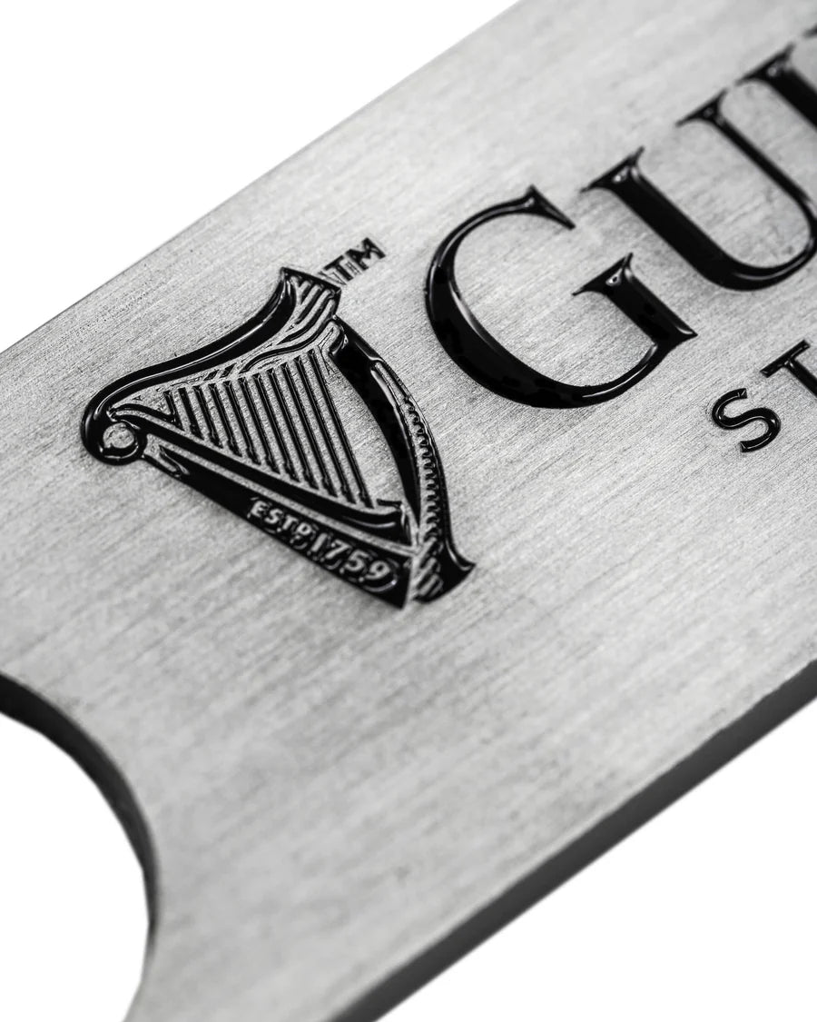 The Guinness Barman Bottle Opener from Guinness Webstore US features the iconic harp logo and "ESTD 1759" engraving—a classic, metallic bar tool ideal for any home bar.