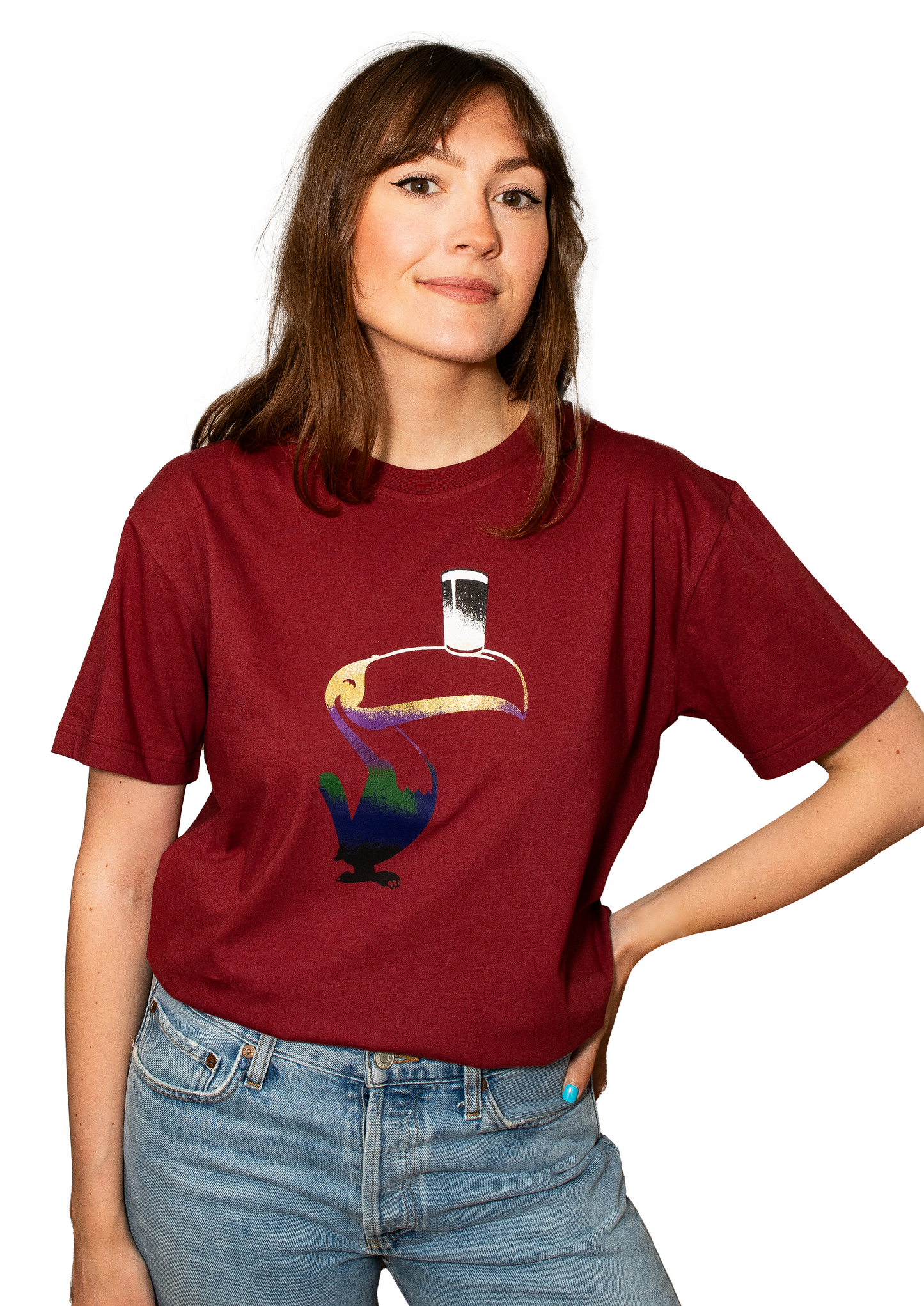 A person wearing the Guinness Liquid Toucan Tee - Red made of 100% BCI Cotton, stands against a white background in blue jeans.