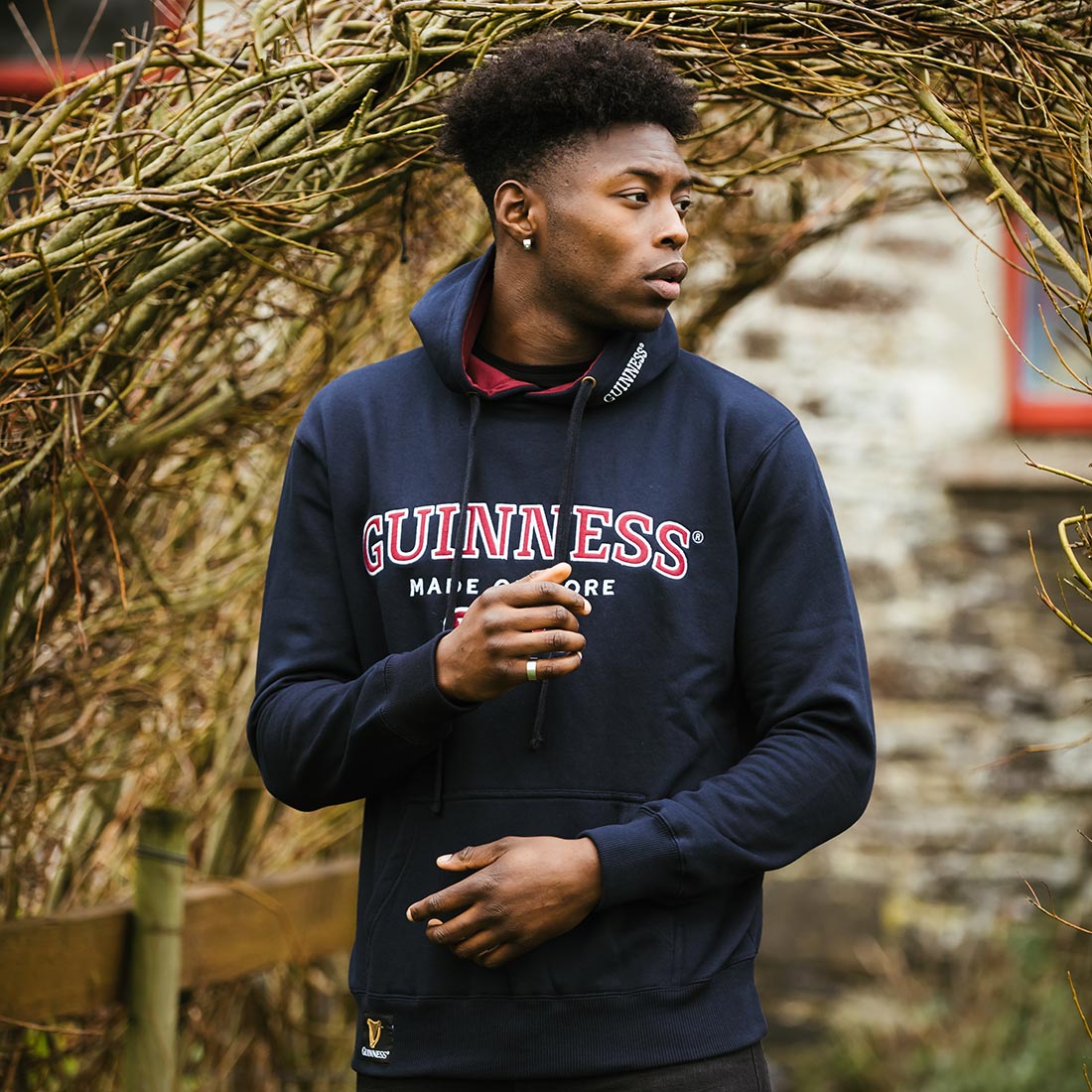 A young man wearing an embroidered Guinness Signature Navy Hooded Sweatshirt.