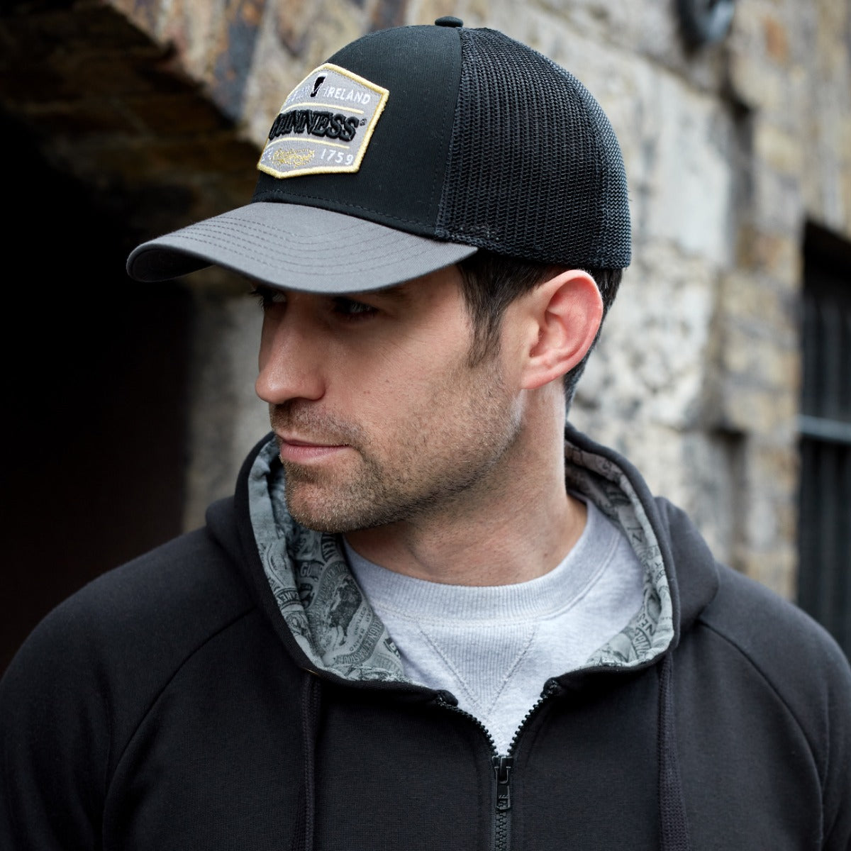 A man wearing a Guinness Trucker Premium Grey with Embroidered Patch Cap made of cotton.