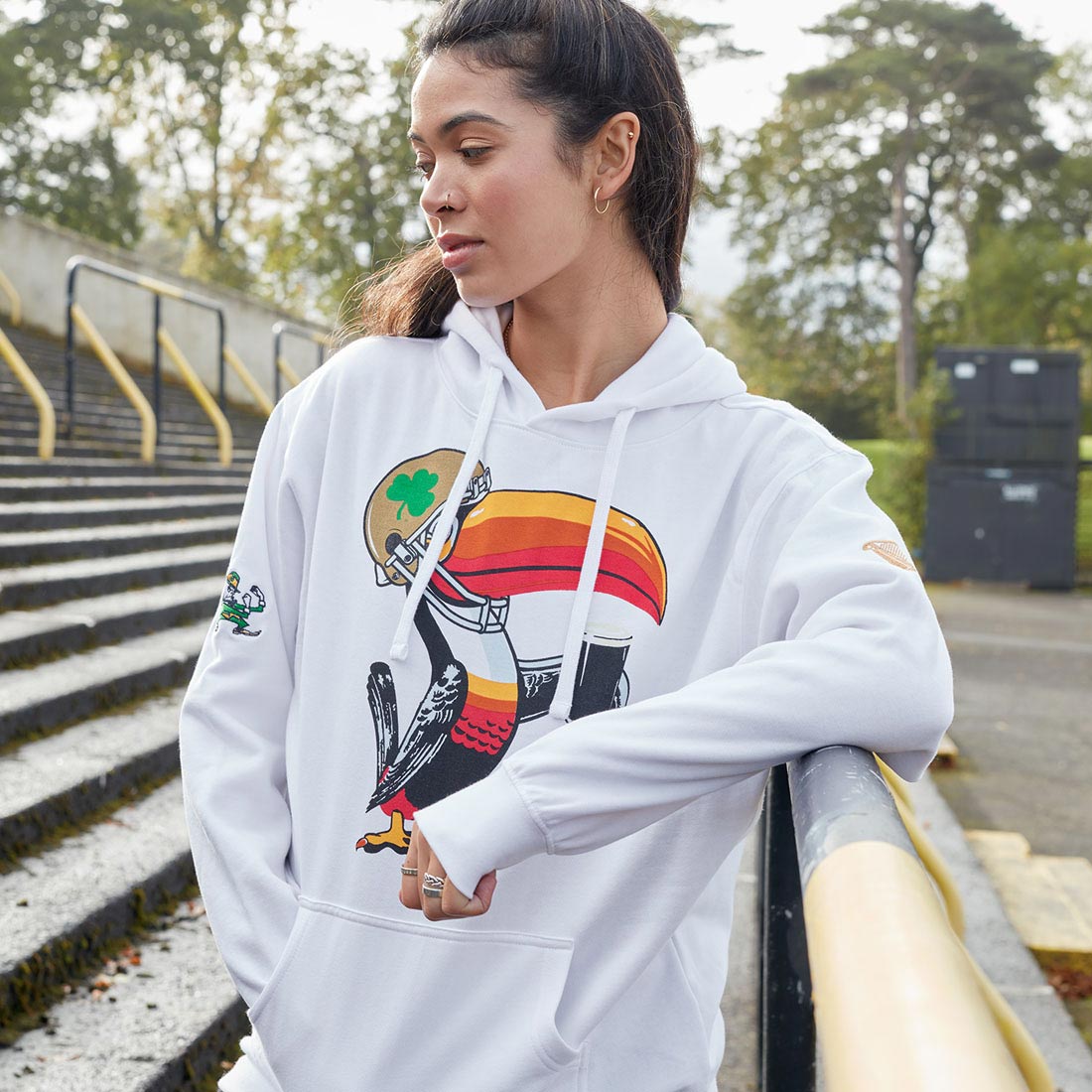 A woman wearing a Guinness Notre Dame Helmet Hoodie White, reminiscent of the iconic Notre Dame Cathedral.