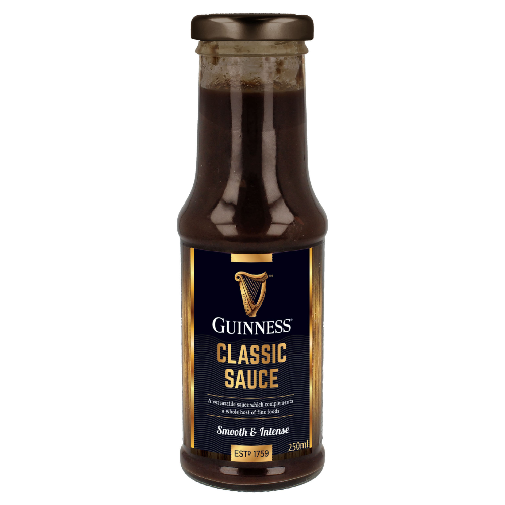 A 295g bottle of Guinness Classic Sauce. The sauce, perfect as a steak sauce, is described as smooth and intense. The bottle features a black label with the Guinness logo and gold accents, making it an ideal foodie gift.