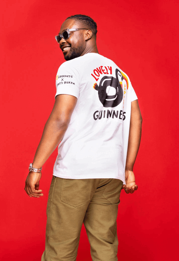 A man wearing a FATTI BURKE "LOVELY DAY FOR A GUINNESS" TOUCAN WHITE TEE in the summer.