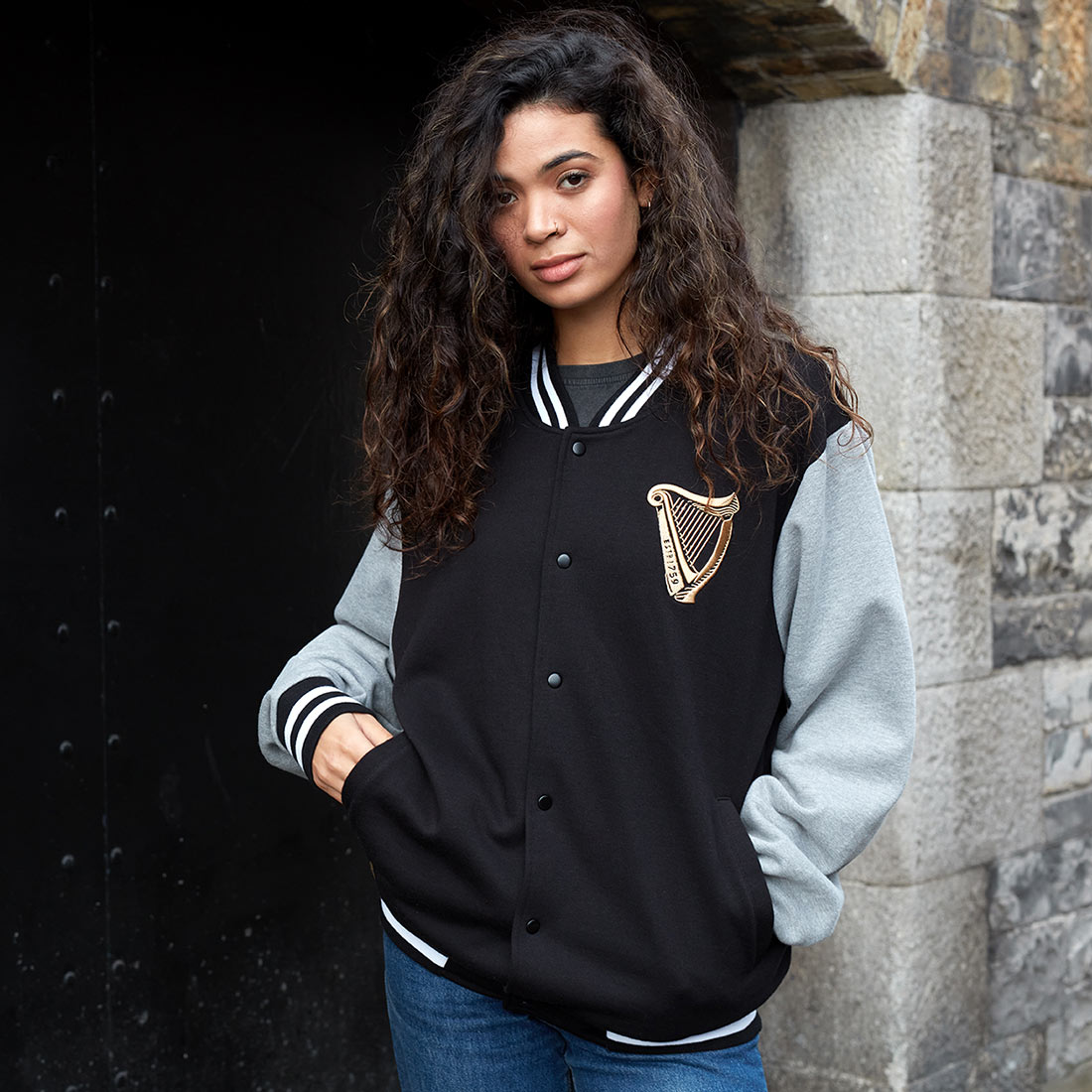 A woman wearing a Guinness Letterman jacket, showcasing the merchandise.