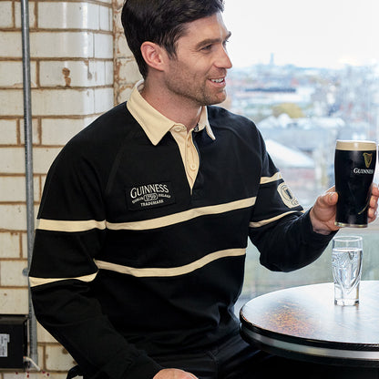 A man holding a pint of Guinness at a Guinness traditional rugby jersey table.