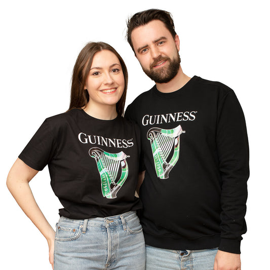 A limited edition Guinness St. Patrick's Day Limited Edition Sweater & Black Tee Collection is being worn by a man and woman in celebration of St. Patrick's Day.