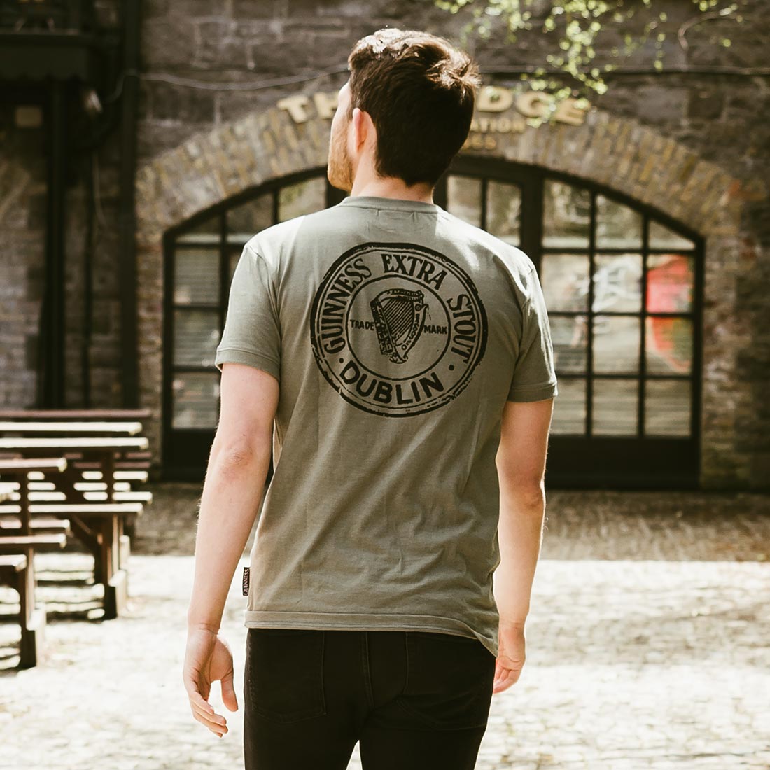 The back of a man wearing a Guinness Green Heathered Bottle Cap Tee.