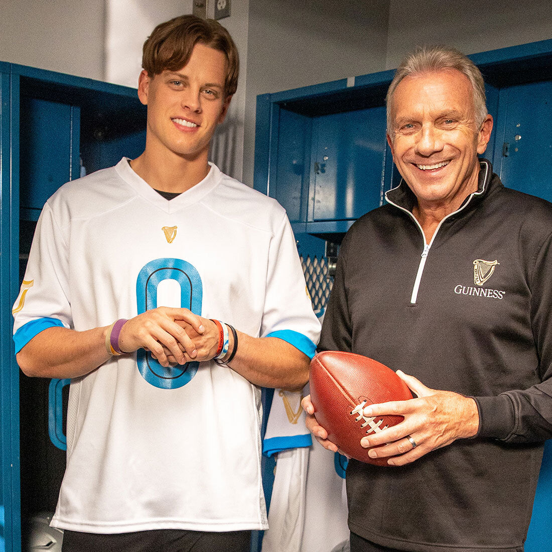 Two men standing next to each other in a white locker, wearing Guinness 0 Football Jerseys - White and holding Guinness 0 from the Guinness Webstore US.