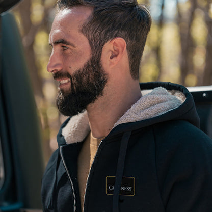 A cozy man wearing a Guinness Sherpa Lined Hoodie with a bearded face.