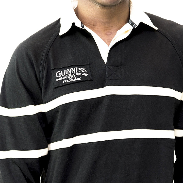 A man wearing an authentic Guinness Traditional Rugby Jersey, crafted from cotton jersey fabric, showcasing the classic black and white rugby look.