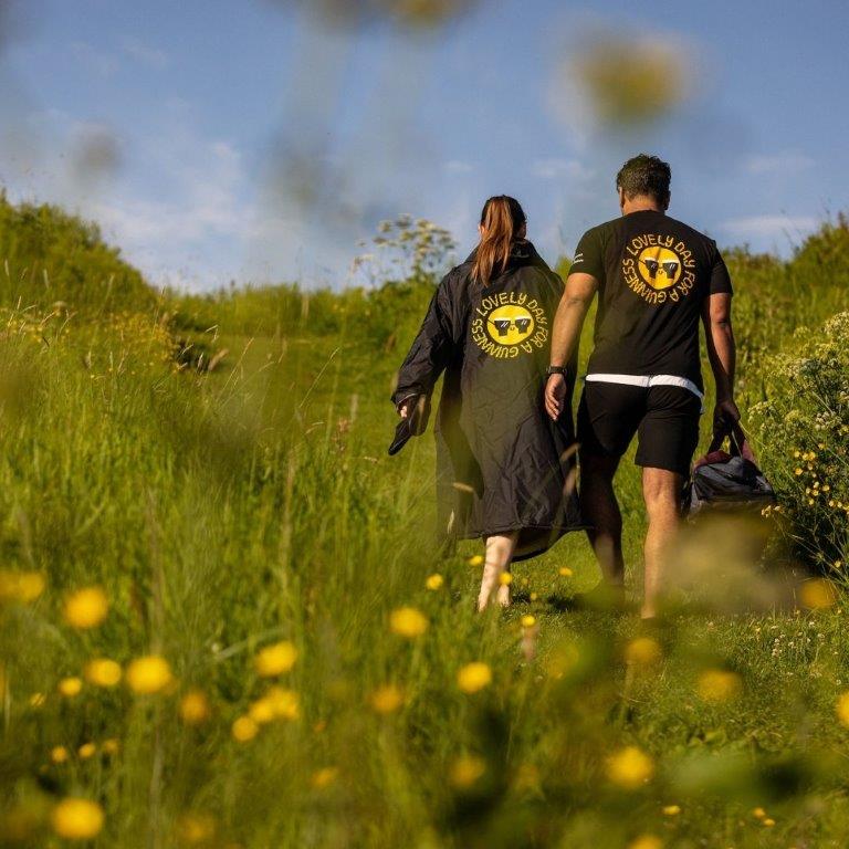 A man and woman, wearing Guinness black t-shirts, walking through a field of summer flowers.