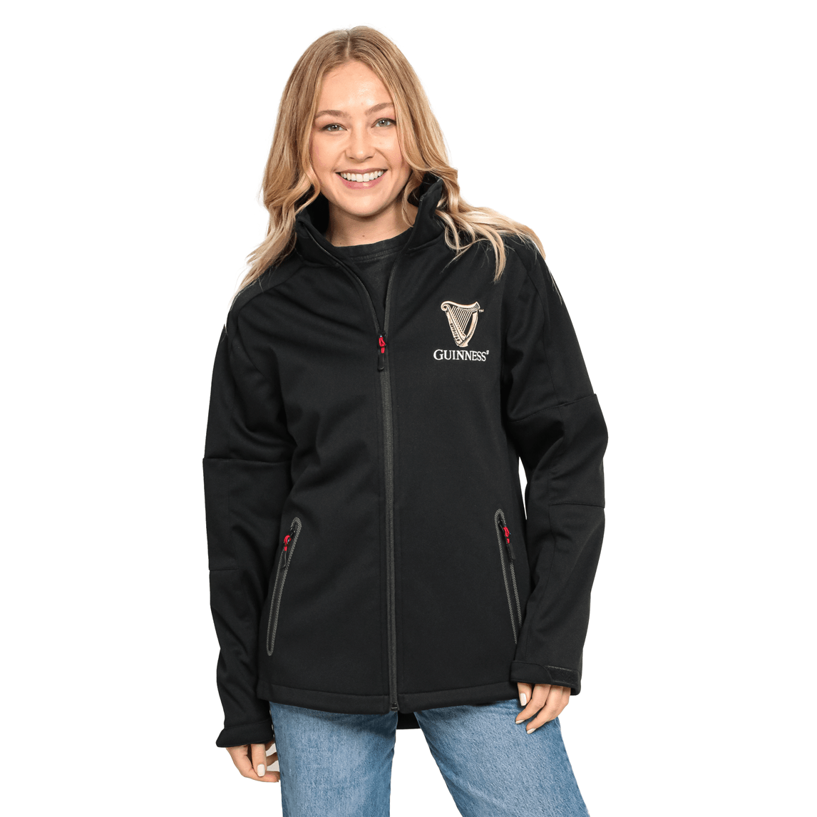 A smiling person with long, light hair wears a black Guinness Soft Shell Waterproof Jacket and light blue jeans.