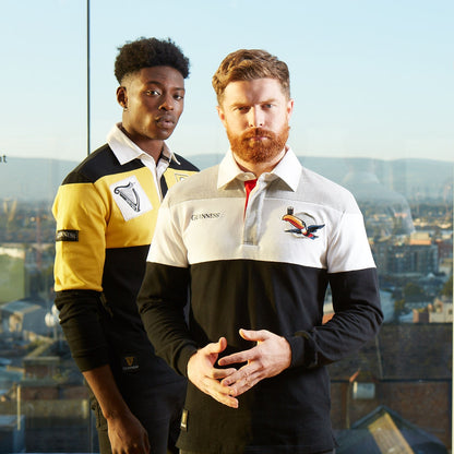 Two men wearing Guinness Toucan Rugby Jerseys standing next to each other in front of a city.