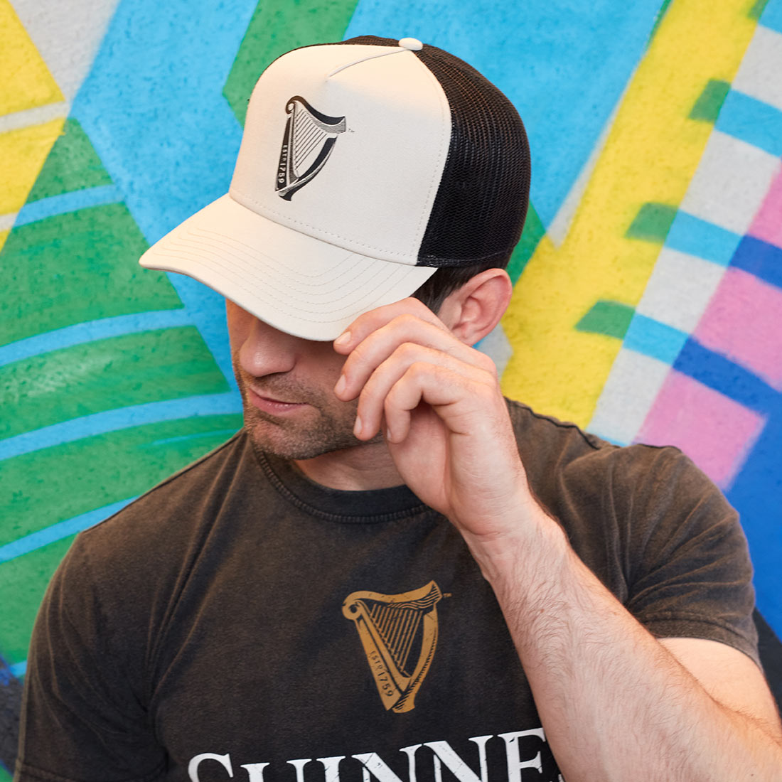 A man wearing a Guinness Premium Beige & Black Harp Hat.