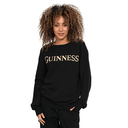 A woman wearing a black Guinness 100% Organic Cotton Jumper with the word Guinness on it.